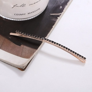 Elegant rose gold rhinestone hair clip with black stones on an aesthetic background