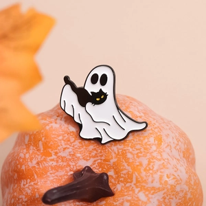Halloween enamel pin featuring a white ghost holding a black cat on a festive pumpkin