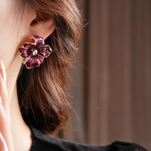 Detail of vintage purple enamel flower earring with gold edges and rhinestone center