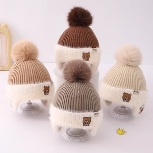 Warm winter knit earflap hat for kids with plush pompom and cute bear embroidery