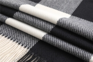Macro shot of plaid scarf fabric texture featuring black and white fringe details