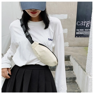 Close-up of beige canvas crossbody bag with black adjustable strap on model