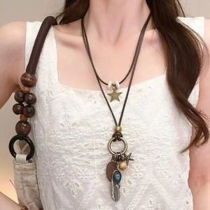 Details einer Boho-Kette aus Wachskordel mit Holzperlen und Ethno-Federanhängern