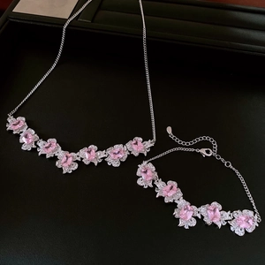 Detail of silver flower jewelry set with pink stones and zircons on black background