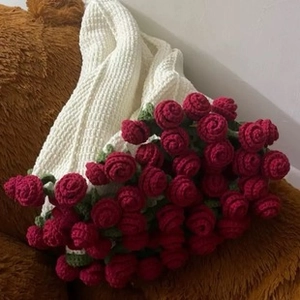 Close-up of handmade red crochet roses on a textured white knitted blanket