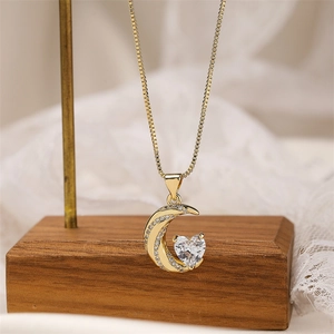 Detailed macro view of gold-plated crescent moon pendant with sparkling heart stone