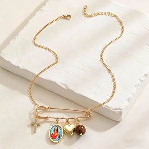 Detail of gold safety pin pendant with cross, religious medal, heart and wooden bead charms