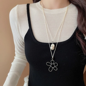 Double-layered necklace with baroque pearl and silver hollow flower pendant on a model