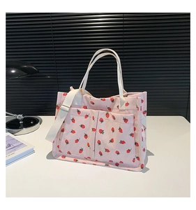 Pink corduroy tote bag detail showing strawberry print and dual front pockets