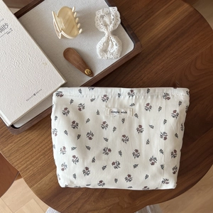 Detail of floral cotton makeup bag with 'simple wish' label on a rustic wooden table