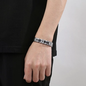 Close-up of a men's stainless steel bracelet with black carbon fiber inlay worn on wrist