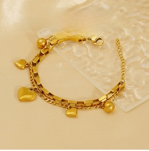 Détail d'un bracelet double couche à breloques en forme de cœur sur fond de soie champagne