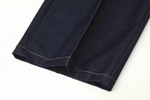 Détail de l'ourlet en denim bleu foncé avec des coutures orange contrastées et du sergé