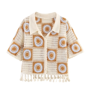 Detail of crochet knit polo shirt with blue sunflower patterns and tassel pendant charm