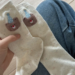 Detail of cream crew socks with colorful dots and 3D plush bear wearing a party hat