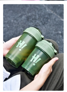 Close-up of dual green translucent plastic shaker cups with H! logo held by hands