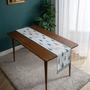 Christmas table runner with pink reindeer and green pine trees on grey fabric with tassels