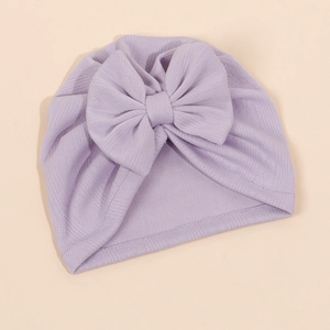 Détail d'un bonnet tricoté lavande pour bébé avec gros nœud et tissu côtelé aéré