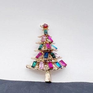 Macro detail of Christmas tree brooch with colorful baguette rhinestones and gold base