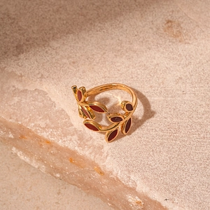 Detailed close-up of vintage gold vine ring with deep red enamel leaves on stone