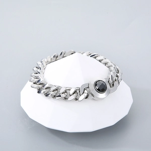 Men's 11mm silver Cuban link necklace with black crystal skull clasp on white pedestal
