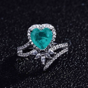 Macro detail of pear-cut emerald gemstone with micro-pave diamond setting on silver ring