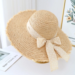 Detailed texture of handwoven raffia straw hat with floral ribbon bow and frayed brim