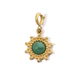 Detail of a gold stainless steel sunburst pendant with a round green gemstone center