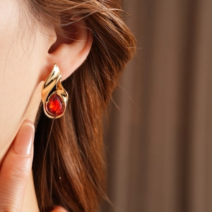 Primo piano di orecchini vintage in oro con pietra a goccia rossa indossati da modella