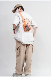 Rear view of model wearing a transparent PVC crossbody bag with orange trim and strap