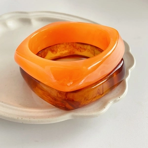 Detail of square resin bangles in translucent orange and vintage amber tortoise pattern