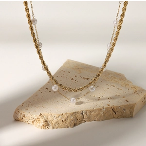 Detail of 18K gold double layer necklace with small pearls on a natural stone base
