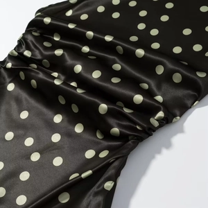 Details von schwarzem Satinstoff mit grünen Punkten zeigt eleganten Fall und Seidentextur