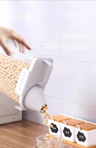 Airtight grain container with funnel spout pouring soybeans into a glass bowl
