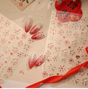 Detail of red and gold heart firework nail stickers with decorative floral patterns