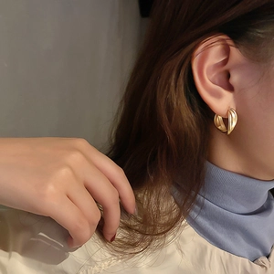 Élégantes boucles d'oreilles créoles dorées multicouches sur modèle au style moderne