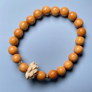 Detailed top view of a sandalwood bracelet with a carved lotus pendant and diamond spacers