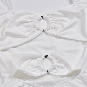 Detail des weißen Langarmkleids mit Metallring-Ausschnitt und geraffter Stoffstruktur