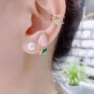 Detailed close-up of pink tulip and pearl earrings with golden triangle ear cuff
