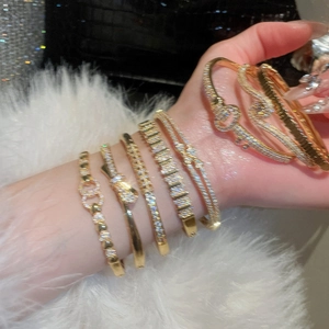 Detailed view of layered 18k gold plated bracelets with zircon and bow charm details