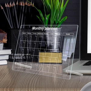 Detailed macro view of acrylic desktop monthly planner with metal stands on wooden desk