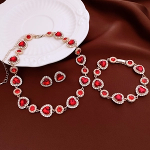 Détail d'une parure en or avec pierres rouges et cristaux sur tissu en soie