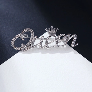Broche Queen argentée avec couronne et diamants sur carte de présentation sobre