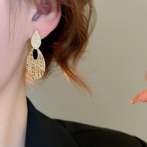 Close-up of textured golden teardrop earrings on model for an elegant minimalist look