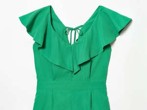 Detail of green V-neck romper with ruffle trim, back lace-up design and waist cut
