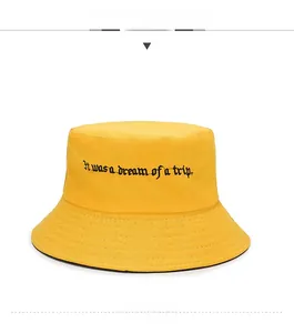 Detail of yellow canvas bucket hat featuring black embroidered English text and stitching