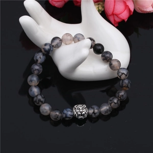 Detail of grey dragon vein agate beaded bracelet with silver lion head on ceramic hand