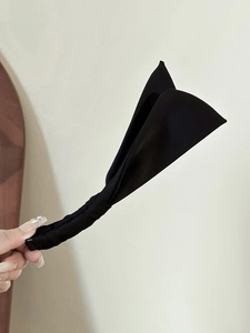 Dettaglio del fermaglio a banana in tessuto nero con elegante design a fiocco di coniglio
