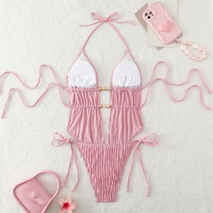 Flat lay of soft pink halter swimsuit featuring waist cut-outs and wooden ring details