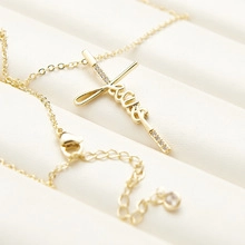 Close-up of gold double snake chain necklace with faith cross pendant and sparkling zircon